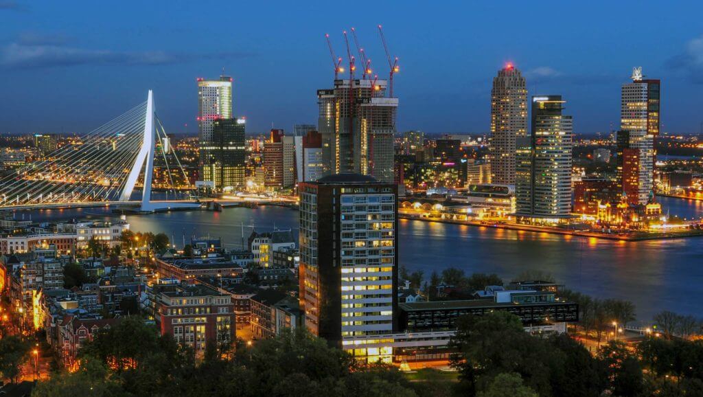 The Rotterdam at dusk in the Netherlands with skyscrapers and bridge lit up