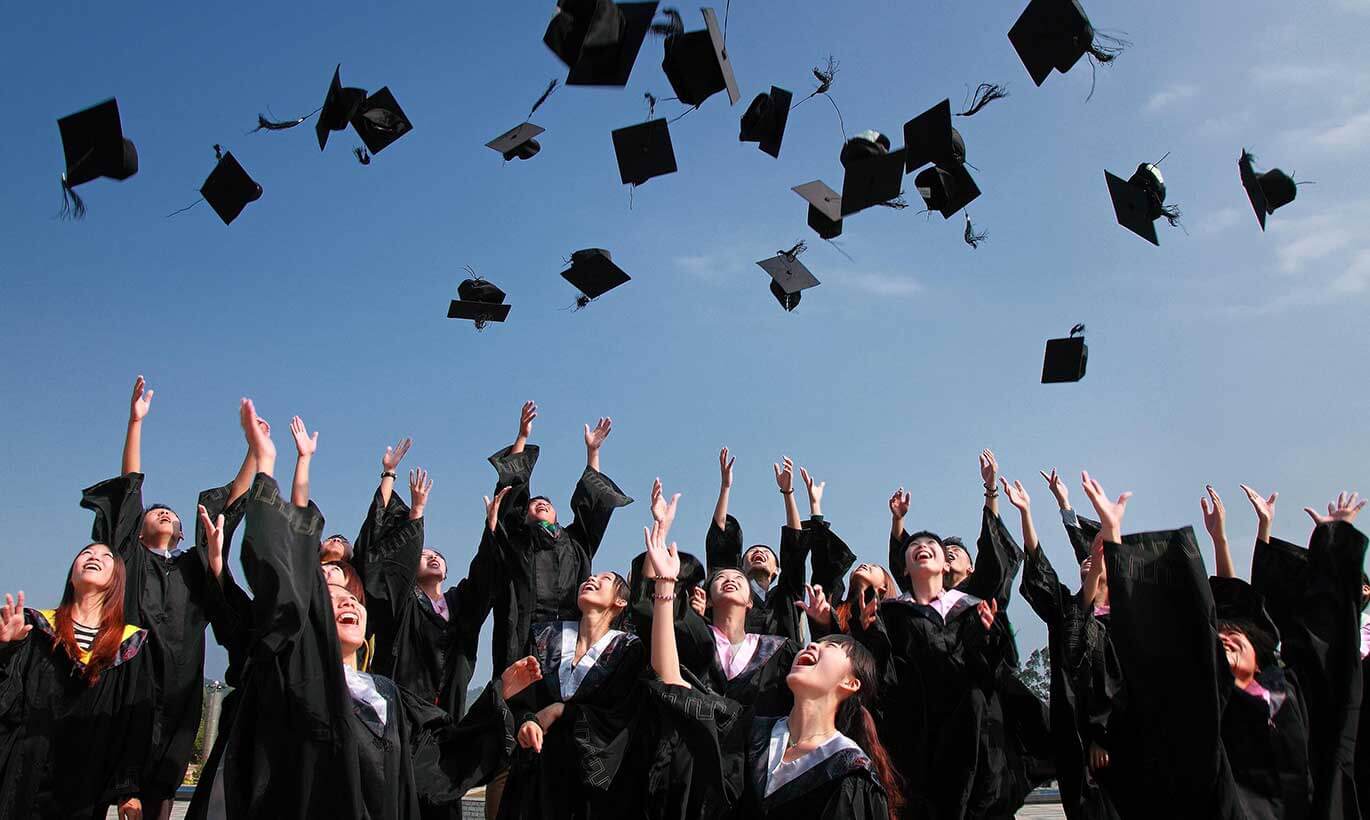 College students throw their caps into the air at a graduation ceremony.