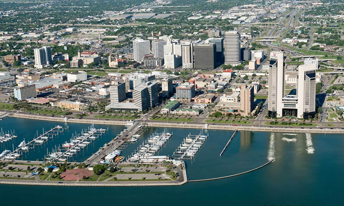 Ships are docked next to tall buildings at the Port of Corpus Christi, Texas.