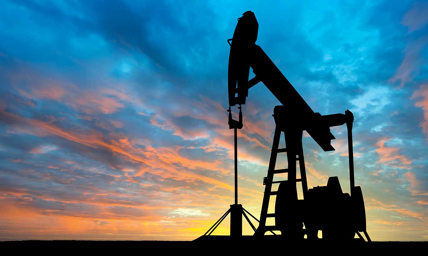 The silhouette of a large oil pump with a sunset backdrop in Texas.