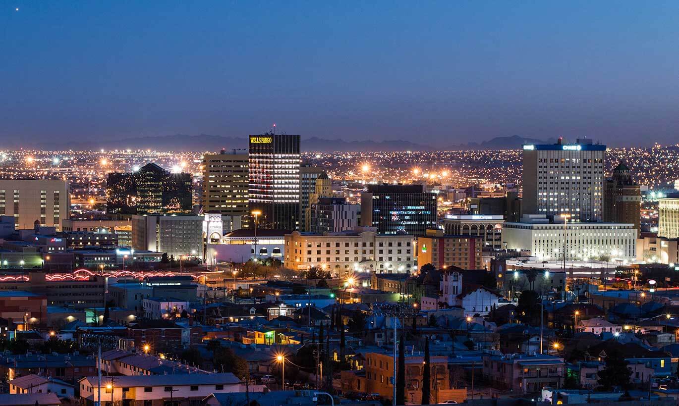 Downtown El Paso is brightly lit up at night with many tall buildings.