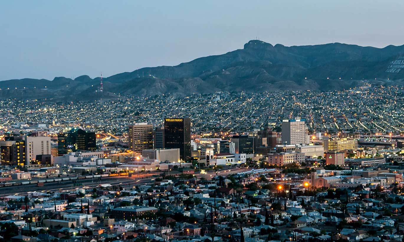 Downtown El Paso is brightly lit up at night with many tall buildings.
