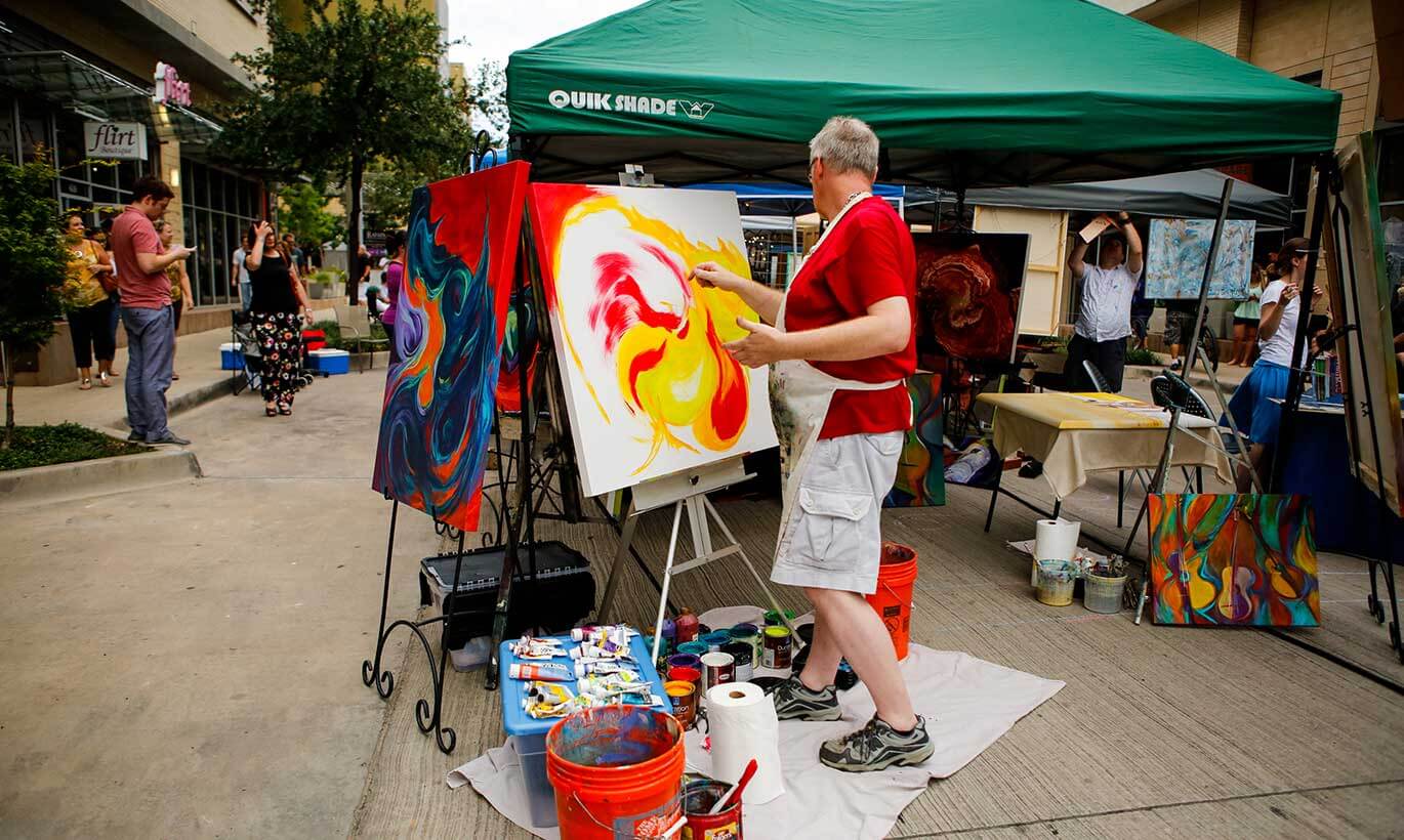A man paints on a canvas at the annual Crockett Artist Fair party in Fort Worth, Texas
