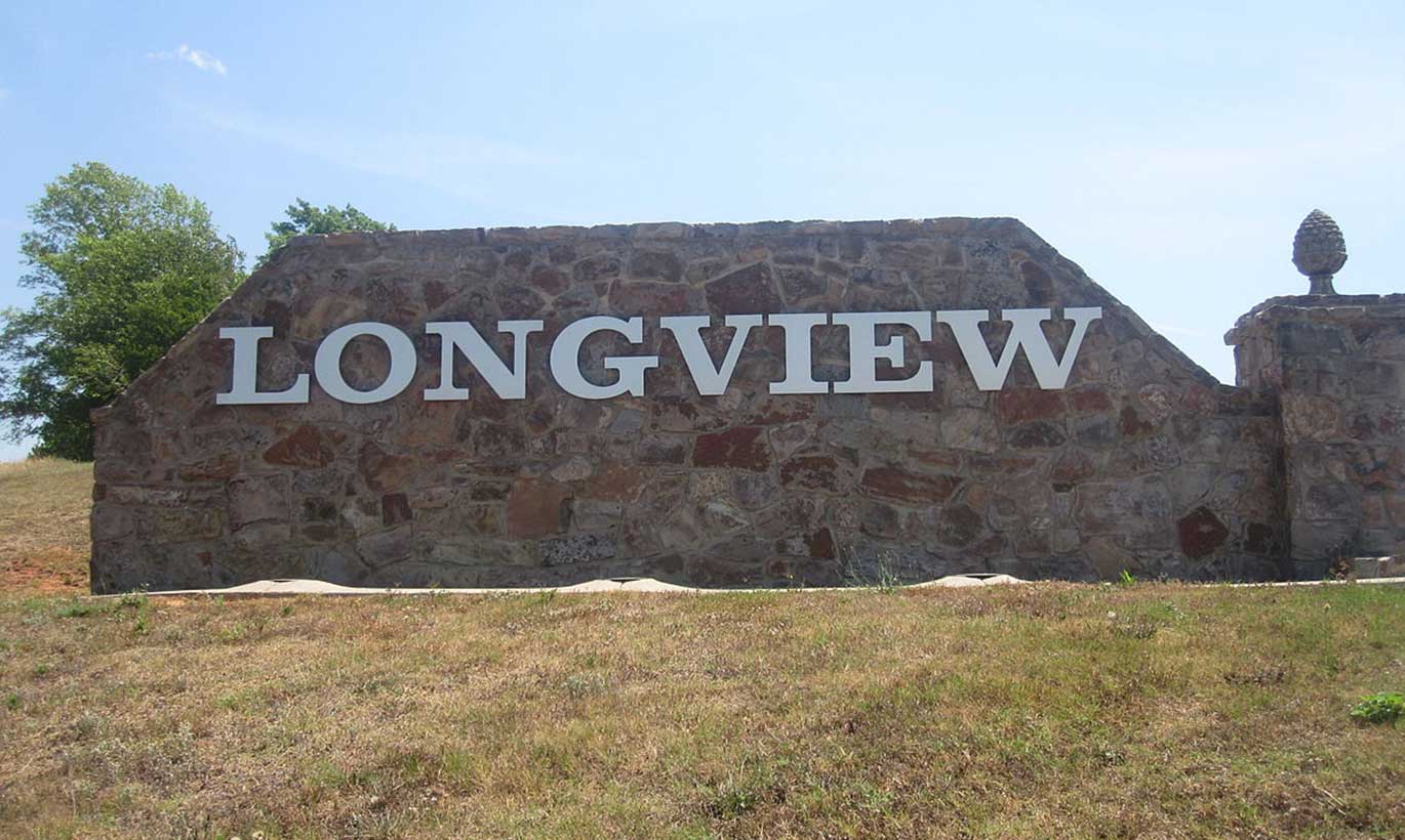 A stone sign depicting the name of the city of Longview, Texas sits on a hill.