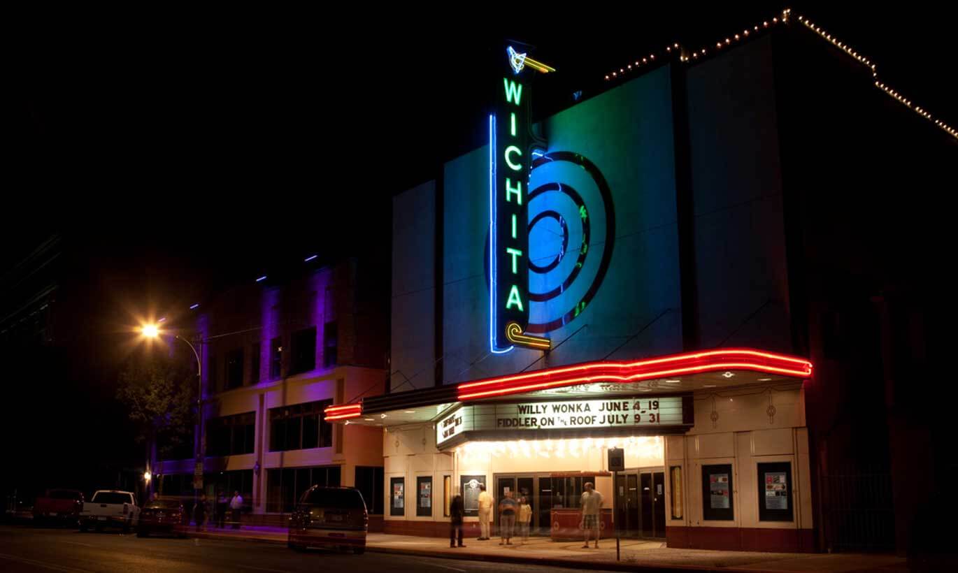 A local movie theatre in Wichita Falls, Texas lit up at night with people standing at the entrance